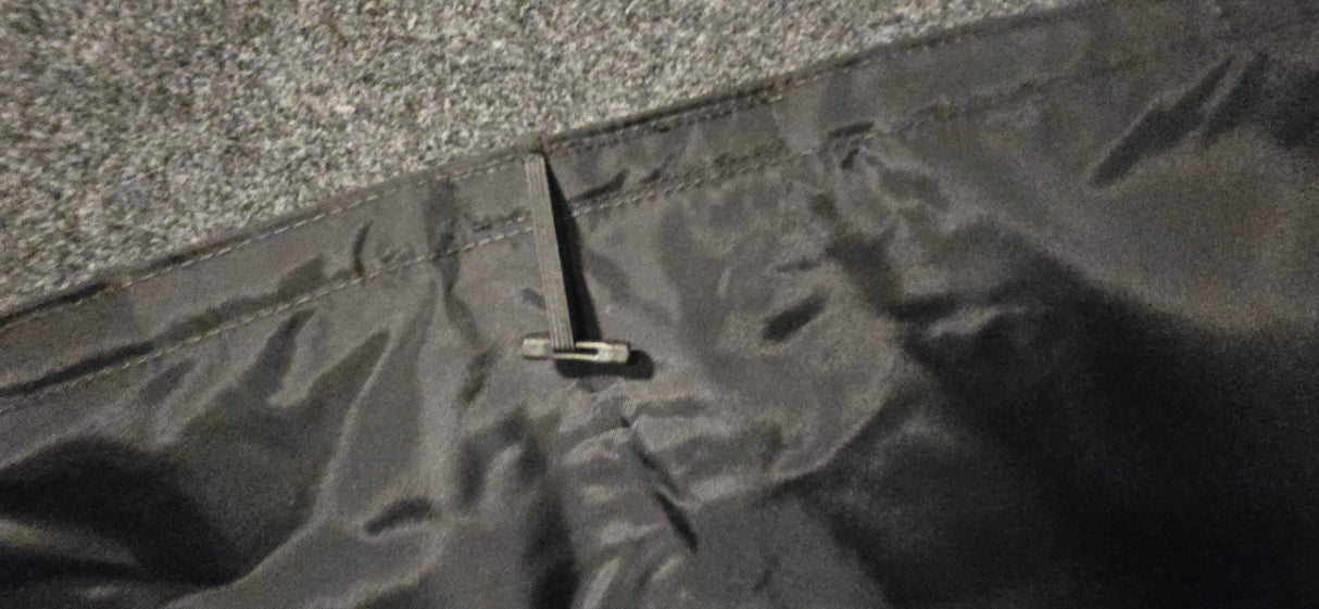 Close-up of the Paha Que Custom Black Out Curtains, featuring a black zipper partially unzipped on dark, shiny blackout fabric with a grey, textured background for enhanced privacy.