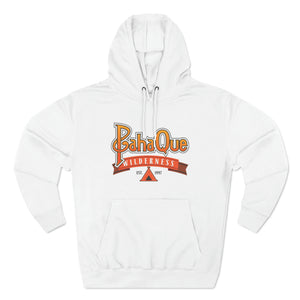 The PahaQue Unisex Premium Pullover Hoodie in white by Printify features BahaQue in yellow and orange, Wilderness in red on a ribbon, Est. 1957 above a small black tent graphic, and a soft fleece lining for added comfort.