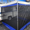 The blue-trimmed screened tent is attached to a white Meerkat Trailer indoors, set before a forest mural and other campers, highlighting the versatility of the Meerkat Trailer Awning by PahaQue from Paha Que Custom.
