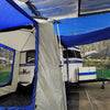 A compact Meerkat Trailer with a blue and gray Paha Que Custom Meerkat Trailer Side Tent for Enhanced Outdoor Adventures and Camping Comfort is set up indoors, backed by a mural of trees, mountains, and rocks, with exposed beams above.