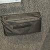 The PahaQue Wilderness PahaQue Gear Pouch, a black heavy-duty zippered pouch with Velcro patch, is attached to a gray felt wall beside a white panel with two black dials and display—ideal for organized trailer gear storage.