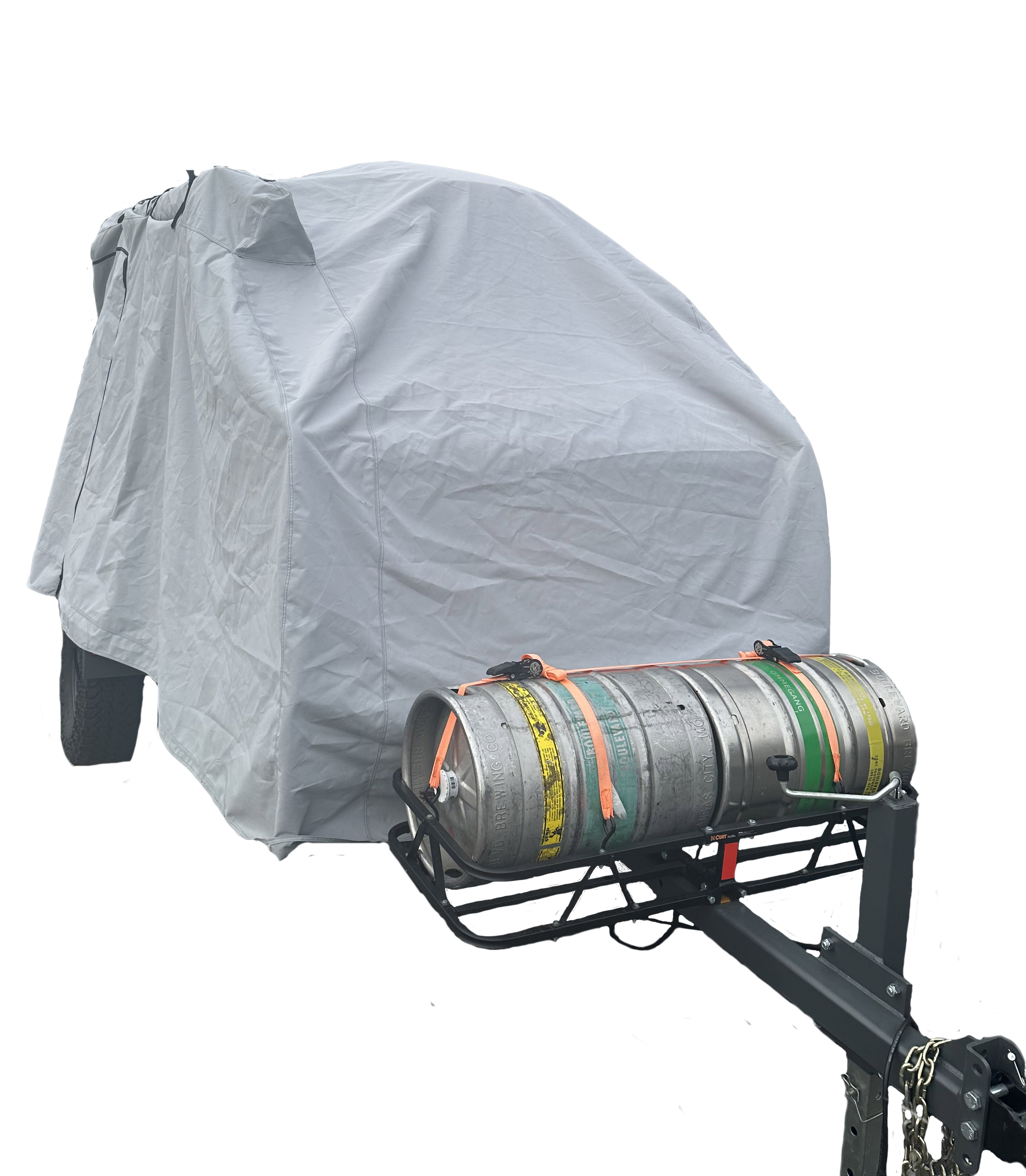 A vehicle is protected by a Paha Que Custom Campinawe Trailer Cover made of heavy-duty MagnaTuff fabric, with a front metal rack holding two strapped-down beer kegs—one silver, one striped.