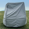 The Hero Trailer Cover by Paha Que Custom, made with heavy duty MagnaTuff fabric for weather-proof protection, is zipped and creased as it stands on a grassy field beneath a clear blue sky with faint mountains in the background.
