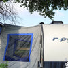 A Forest River R-Pod Trailer Side Tent by PahaQue for Enhanced Camping Comfort is pitched under a large tree, showcasing its blue-trimmed window and easy setup with camping gear—perfect for outdoor adventures. Brand: Paha Que Custom.
