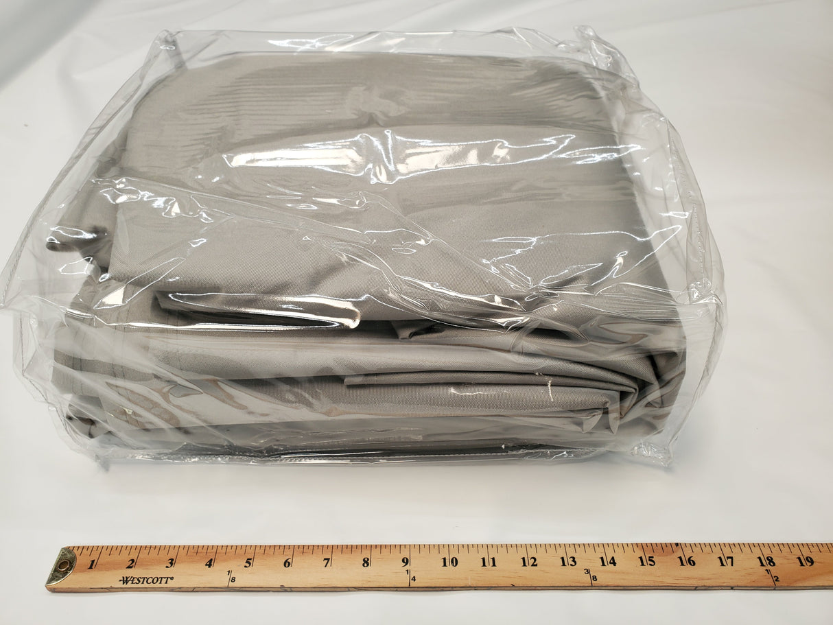 A folded set of gray bed sheets in a clear plastic bag sits on a white surface beside a ruler, reflecting the durability of Paha Que Custom’s Ultimate Toys Trailer Cover, known for its weather-resistant protection.