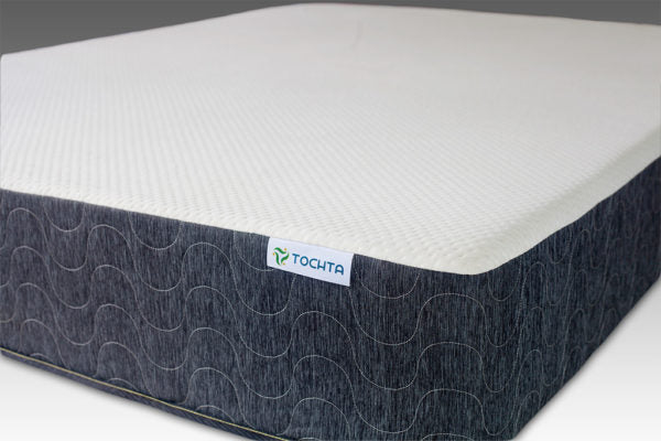 A close-up of the PahaQue Wilderness Utopia Mattress, showcasing its white top and dark gray wave-patterned sides against a neutral background, emphasizes the premium support it offers.
