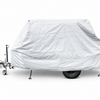 A trailer is parked on a white background, covered by the Hero Trailer Cover by PahaQue - CLEARANCE SALE. The light gray protective tarp from Paha Que Custom shields the trailer, with its wheels and towing hitch partly visible beneath.