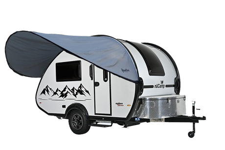 A small white teardrop camper with mountain graphics features a Paha Que Custom NuCamp TAB 360 Trailer Visor Accessory for Enhanced Outdoor Protection, a side door, black accents, window, diamond-plate storage box, and trailer hitch.