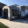 A Paha Que Custom A-Frame Trailer Side Tent for Aliner, Chalet, Rockwood, and Jayco 12 and 15 box trailers is set up on a driveway beside a house, its attached screened area providing extra space under the clear sky.