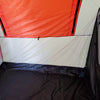 The image shows the inside corner of a Paha Que Custom NuCamp TAB 320 Trailer Side Tent for TAB and Boondock trailers, with a black floor, white walls, an orange upper section, a zippered seam, and part of the BOONDOCK logo on the right.
