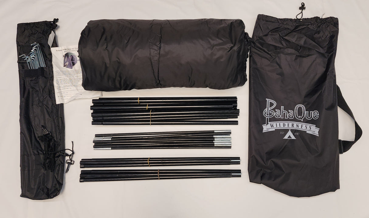 Paha Que Custom 5x7 Trailer Side Tent Screen Room kit shown on a white surface with two black carry bags, folded tent fabric, instructions, stakes, and tent poles—perfect for camping or as a trailer side tent. PahaQue Wilderness logo visible.