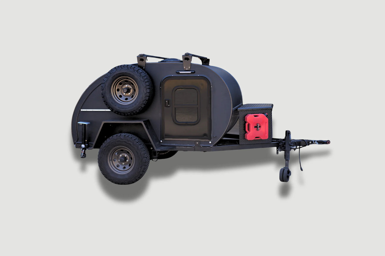 A compact, black off-road teardrop trailer with rugged tires, a spare tire mounted on the side, a red fuel canister in front, and a small entry door, set against a light gray background.