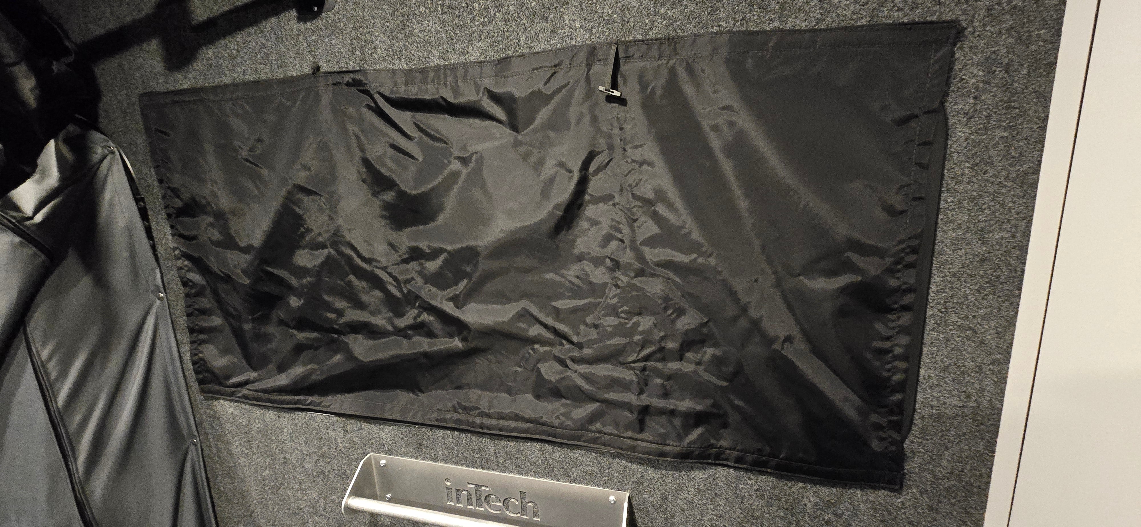 A Paha Que Custom Black Out Curtain, made from privacy blackout material, is attached to a gray carpeted wall above a silver metal plate engraved with inTech.