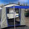 A Paha Que Custom Meerkat Trailer Side Tent for Enhanced Outdoor Adventures and Camping Comfort is set up beside a compact white trailer indoors, with another trailer and a nature mural visible in the background.