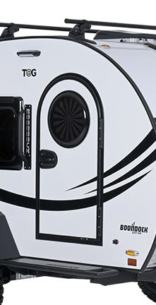 Close-up of the side door of a white teardrop camper trailer with black accents, featuring a Paha Que Custom Toy Hauler Mesh Door/Solid Room Divider for insect protection; the words T@G and BOONDOCK are visible on the exterior.