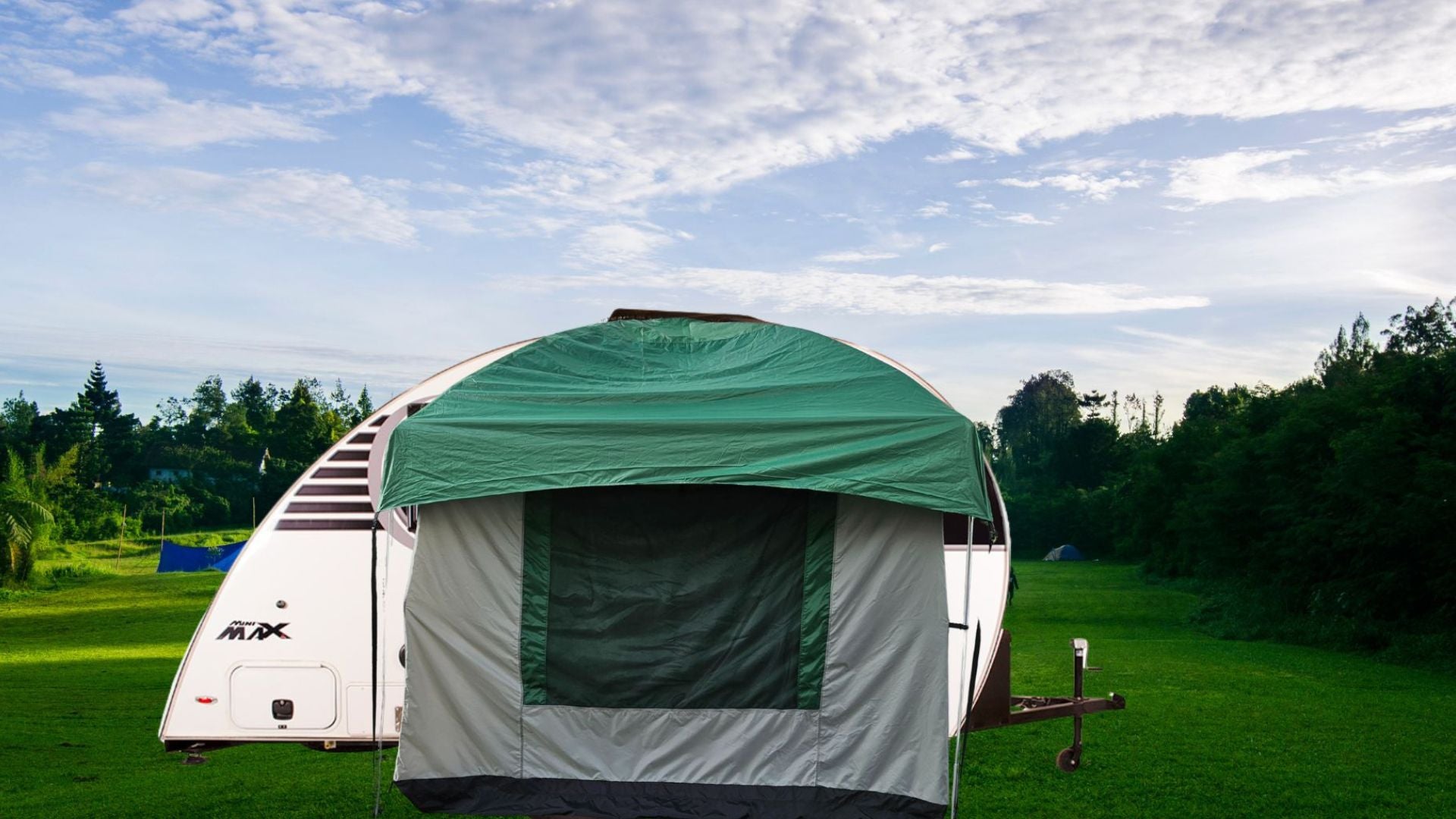 The Paha Que Custom 10x10 Side Mount Screen Room Tent for camping is set up on grass in front of a white camper trailer, with trees in the background and a partly cloudy sky above.
