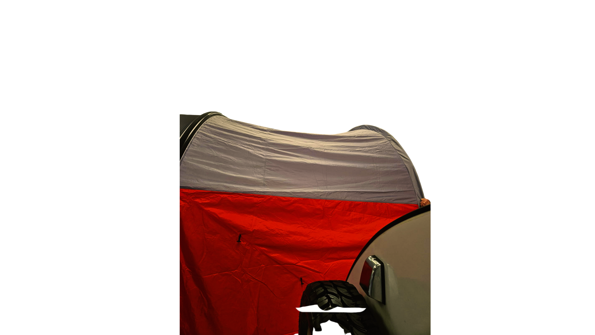 A NuCamp TAB 360 Trailer Awning by Paha Que Custom acts as a waterproof shelter, set up at night and attached to a vehicle with a spare tire and side mirror visible in the darkness.