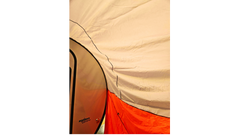 Close-up of a beige, orange, and white tent showing its fabric texture and seams, with part of a NuCamp TAB 360 Trailer Awning by Paha Que Custom and its teardrop camper visible on the left.