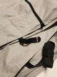 Close-up of the PahaQue Wilderness Aero Teardrops Trailer Cover shows its light gray fabric, black zippers, straps, and a padded handle visible in the lower right corner. One zipper is partially unzipped.