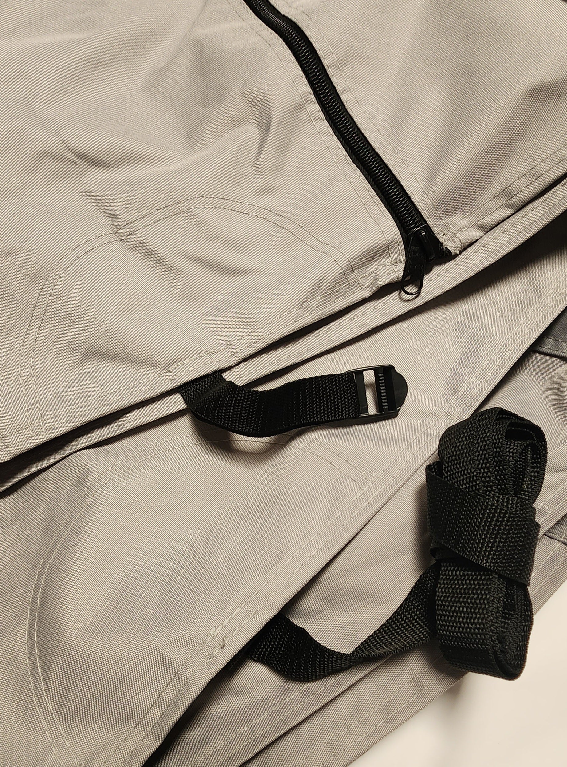 A close-up of a light gray bag featuring black straps, a plastic buckle, and a zipper—design details inspired by the OUT108 Hiker 5x10 Trailer Cover from Paha Que Custom.
