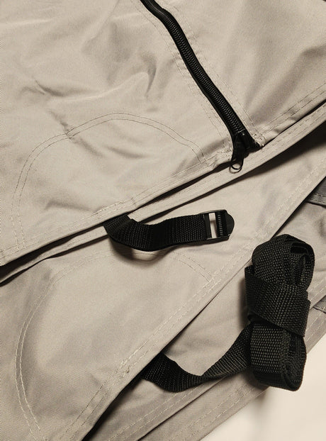 A close-up of light gray MagnaTuff fabric with visible stitching, a black zipper, and black adjustable straps with a plastic buckle, part of the Paha Que Custom Ultimate Toys Trailer Cover By PahaQue Durable Weather-Resistant Protection.