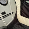 A close-up of the Paha Que Custom NuCamp TAB 320 Trailer Side Tent for TAB and Boondock Trailers shows the tent’s black and cream fabric with mesh window, partially enclosing the camper door—an ideal comfort accessory.