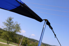 Close-up of the All Purpose Portable Vehicle Awning by PahaQue, featuring a blue canopy corner with pole and securing rope. This PahaQue Wilderness shade is perfect for cars, SUVs, trucks, and side by sides—ideal for trips or gatherings outdoors.