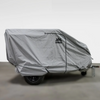 A small off-road trailer is fully protected by the Paha Que Custom Off Grid Trailer Covers Premium Protection for Most OffGrid Trailers, a fitted gray, weather-resistant cover with logo and zipper, parked indoors with hitch and chains partly visible.