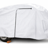A compact trailer is fully protected by a PahaQue Wilderness So-Cal Teardrops Sierra Trailer Cover, with a black zipper, part of the wheel and hitch visible, and one wheel resting on a wooden block.