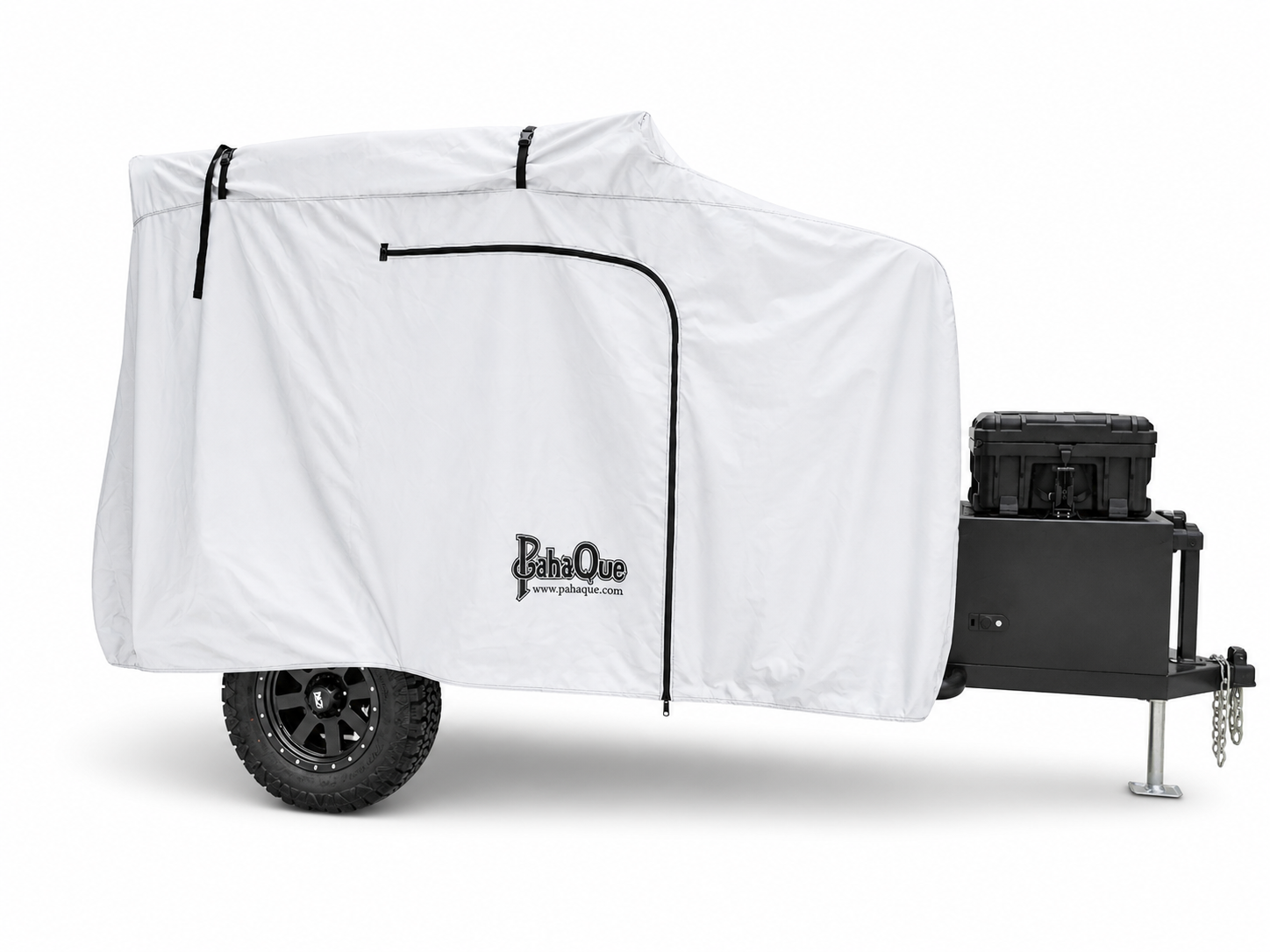 A Cedar Ridge camper is shielded by a white Cedar Ridge Vega XT AT Cover from Paha Que Custom for premium weather protection. Features include a single rugged tire, black storage box, and a metal jack stand at the front.