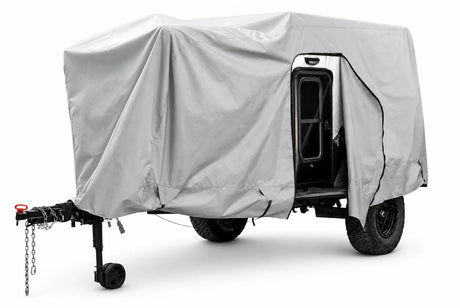 The compact trailer is protected by the Paha Que Custom Xpedition Trailer Cover for Ultimate Protection and Longevity, which features a light gray custom fit, zippered opening, and reveals the black door and frame while ensuring superior weather protection.