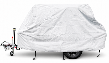 A 6x13 Squaredrop Trailer is protected by the Paha Que Custom Squaredrop Trailer Cover made of heavy-duty MagnaTuff fabric in white, concealing its shape while leaving the wheel, hitch, and support legs visible for easy access.