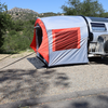 A compact teardrop trailer with a Paha Que Custom NuCamp TAB 320 Trailer Side Tent for TAB and Boondock Trailers is set up on a gravel campsite among trees and hills under a clear sky.