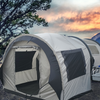 A spacious gray Paha Que Custom NuCamp TAB 320 Trailer Side Tent for TAB and Boondock Trailers is set up outdoors by trees, with camping gear on a table beside it and a mountain sunset in the background—an ideal trailer camping accessory.