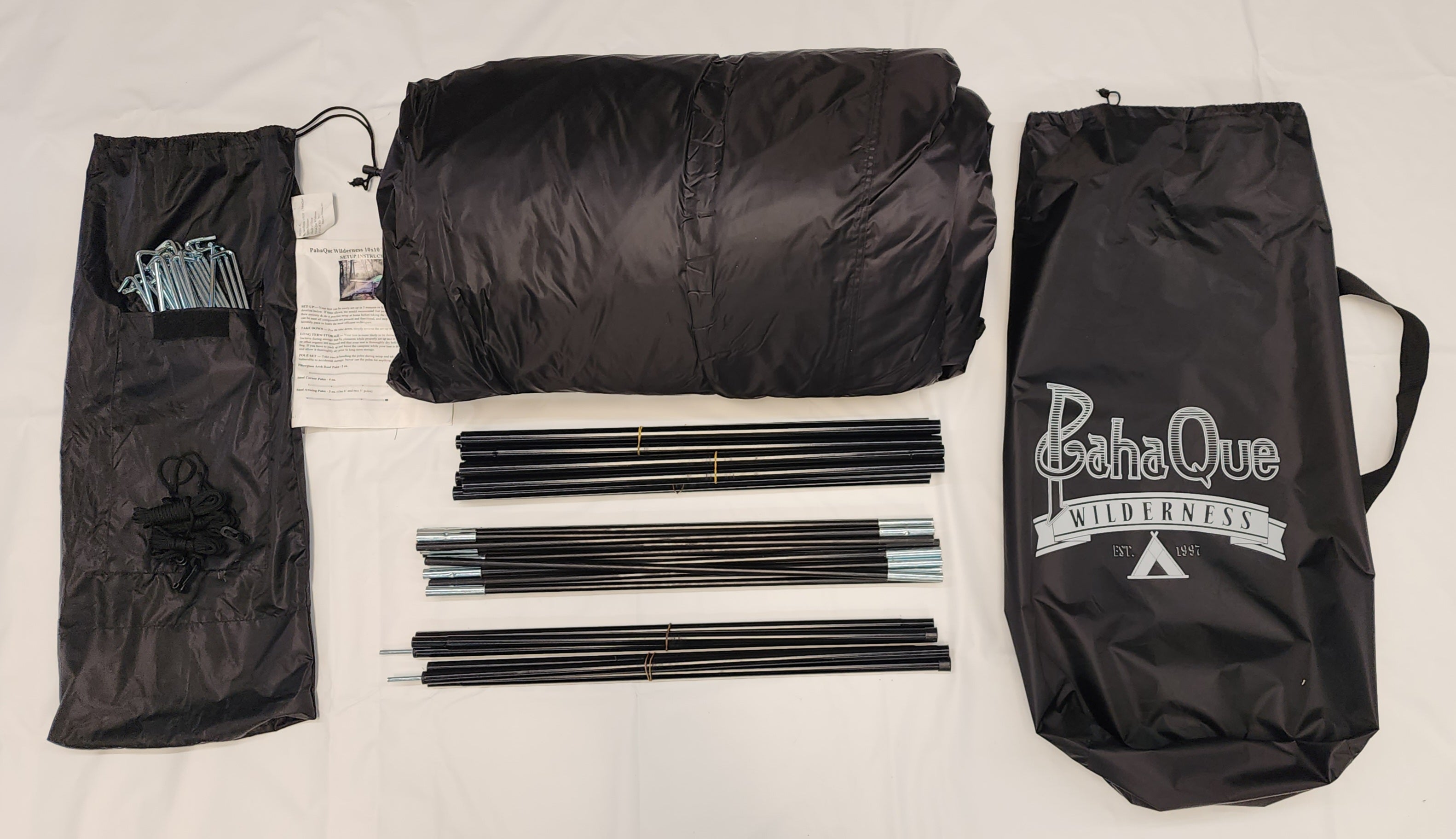 A disassembled Paha Que Custom 10x10 Side Mount Screen Room Tent kit—includes rolled tent, two bags, poles, stakes, and instructions—shown neatly arranged on a white surface, ready for your next camping or outdoor adventure.
